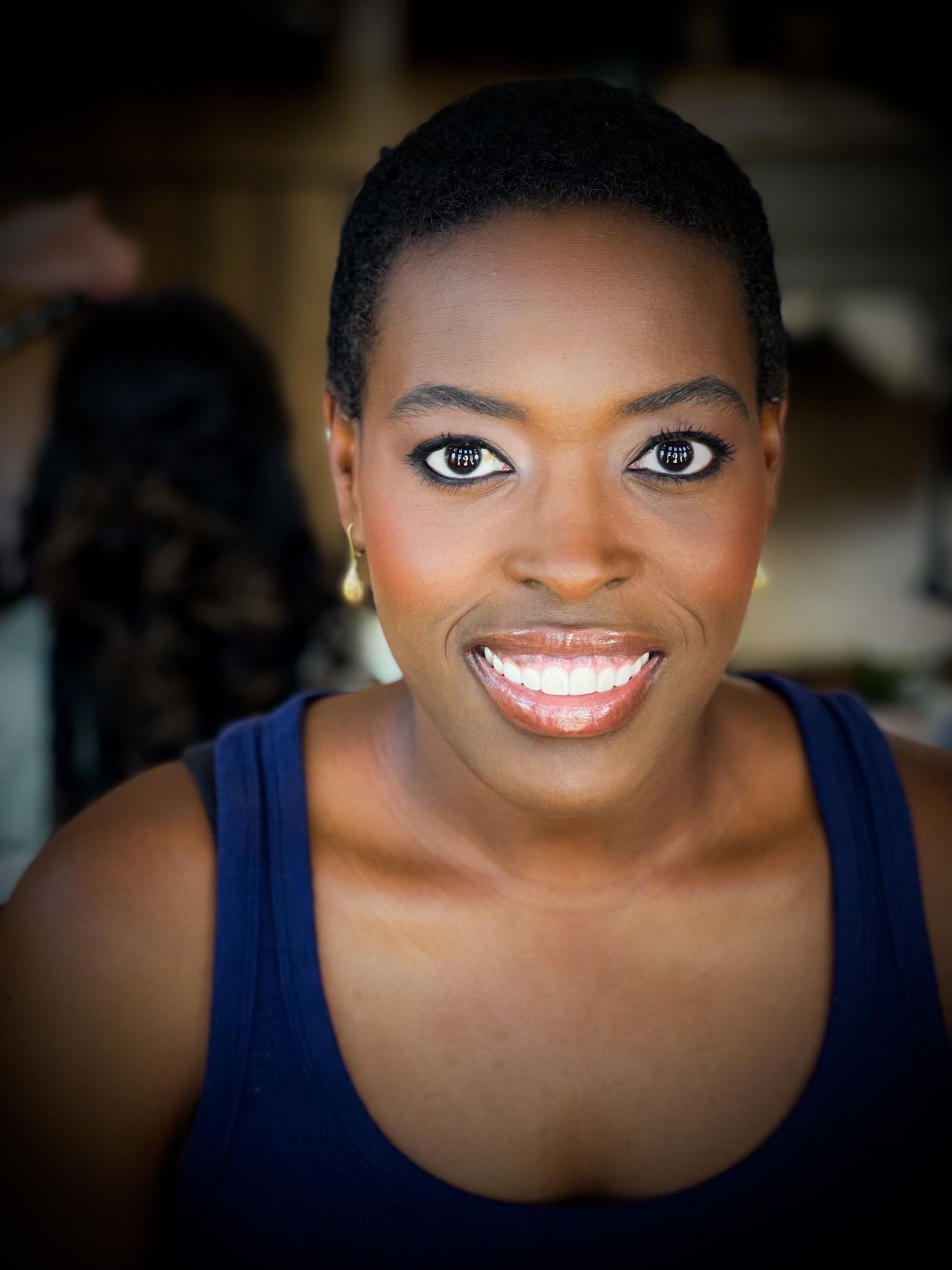 Black bride with short natural hair, glowing skin, defined brows, soft-glam wedding makeup, long lashes, and glossy lipstick.