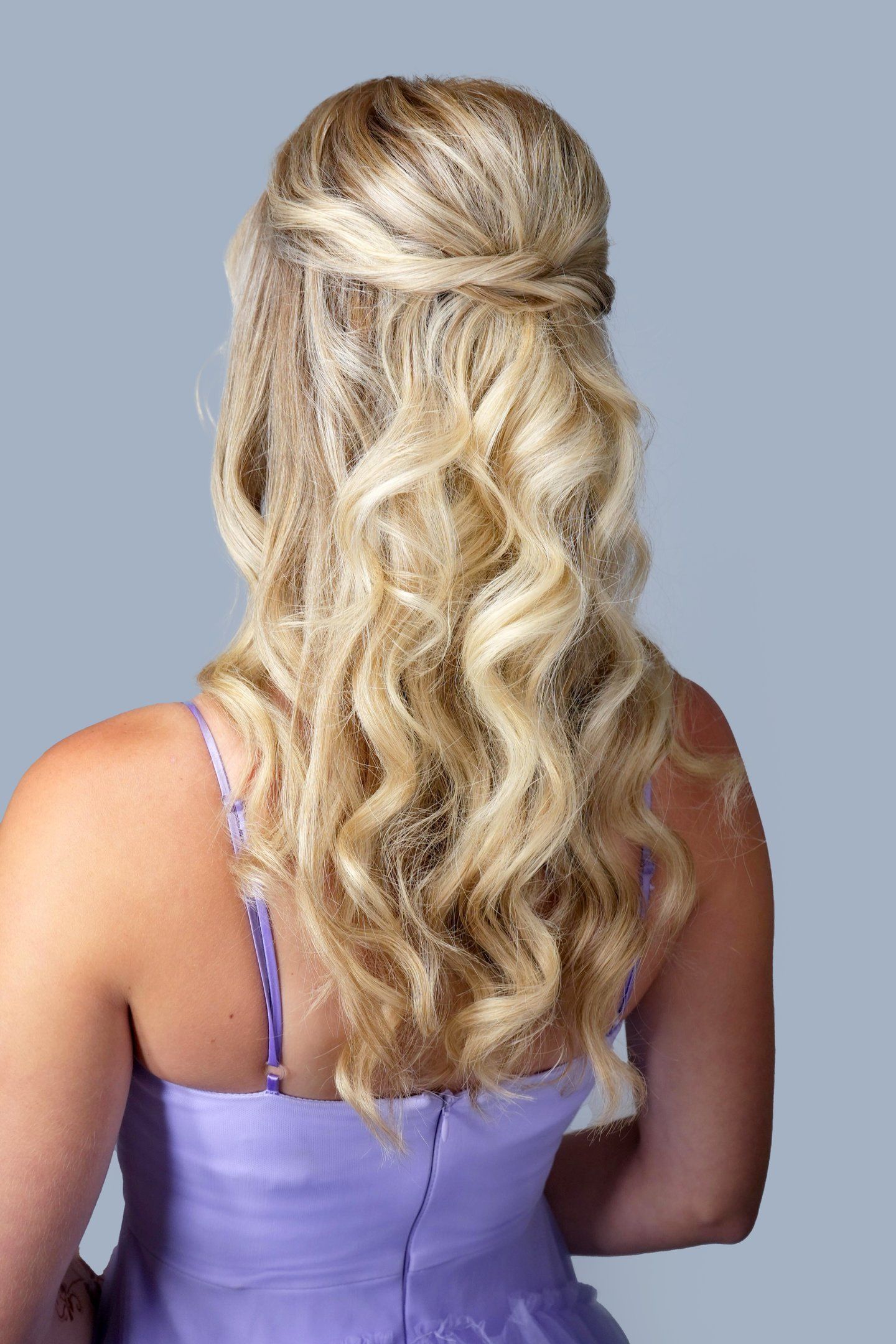 Bridesmaid with blonde hair styled in half up half down curls wearing lavender dress, romantic hairstyle for wedding day.