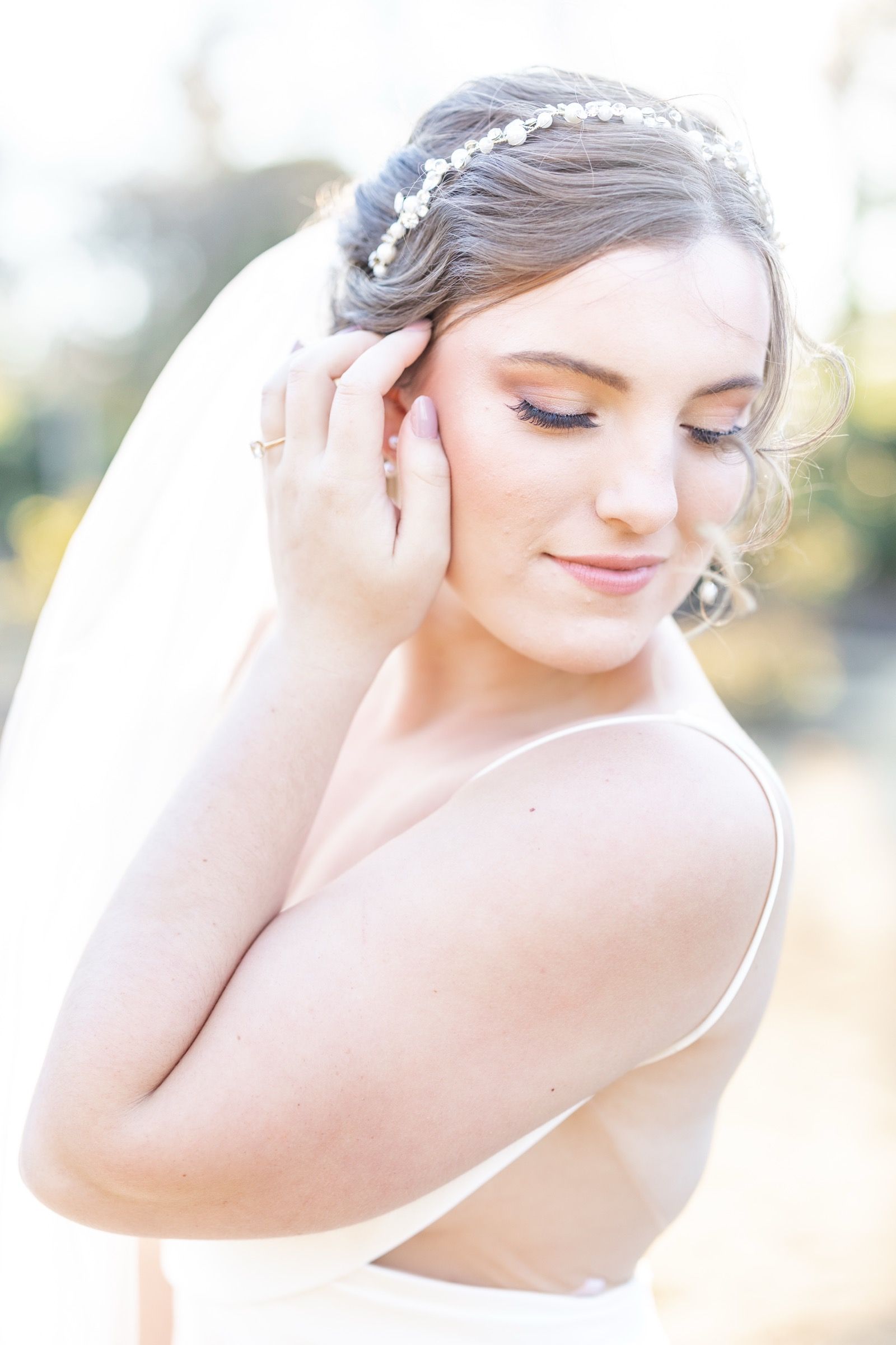 A bride with soft glam and a pearl headband admiring her finished trial look